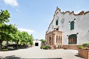 a large white building with a stone driveway at Can Borrell Villa Carmen in Castellar