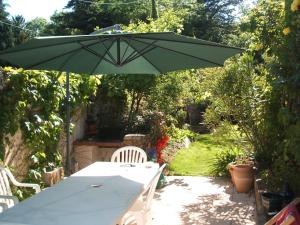 una mesa con una sombrilla verde en un jardín en Maison de charme en Binic