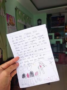 a person holding up a sheet of paper with a drawing at Win's Homestay in Danang