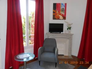 a living room with red curtains and a chair and a fireplace at Hotel Villa Les Cygnes in Nice