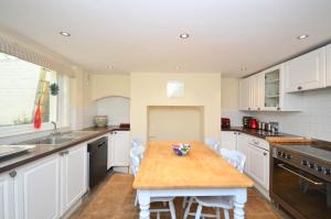 a kitchen with a wooden table and white cabinets at Casa Mar Bella, a Large House with Sweeping Sea and Beach Views in Ramsgate