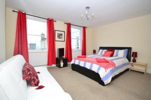 a bedroom with two beds and red curtains at Casa Mar Bella in Ramsgate