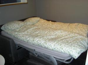 1 cama no hecha en una esquina de una habitación en Elvis Stuga en Östersund