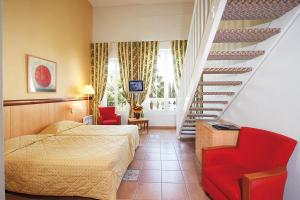 a bedroom with a bed and a staircase with red chairs at Residence Vacances Bleues le Mediterranée in Saint-Raphaël