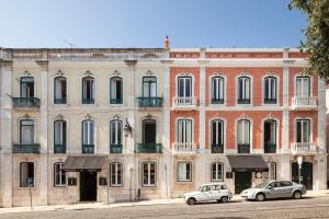 dos coches estacionados frente a un gran edificio en Independente Príncipe Real, en Lisboa