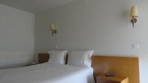 um quarto com uma cama com lençóis brancos e almofadas em Hotel O Mirandes em Miranda do Douro