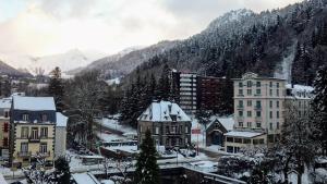 a town covered in snow with mountains in the background at Hôtel de Londres in Le Mont-Dore