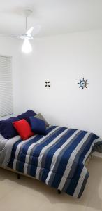 Bett in einem weißen Zimmer mit blauen und roten Kissen in der Unterkunft MoradiaSP - Apartamento Novo Completo 650 M do Metro Guilhermina in São Paulo