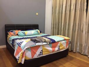Una cama con edredón y almohadas en un dormitorio. en The Loft Imago Studio Suites, Kota Kinabalu, en Kota Kinabalu