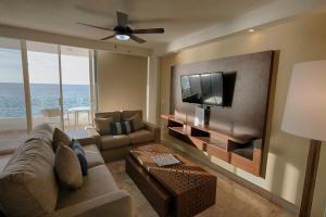 a living room with a couch and a flat screen tv at Costa Sur All Inclusive Resort in Puerto Vallarta