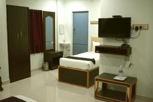 a hotel room with a bed and a flat screen tv at Hotel Apple Park Inn in Tiruchirappalli