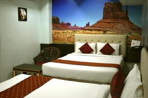 a hotel room with two beds and a painting on the wall at Hotel Apple Park Inn in Tiruchchirāppalli