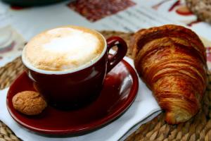 a cup of coffee and a croissant on a table at B&B da Debora in Pisa