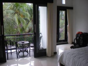 Schlafzimmer mit einem Bett und Blick auf einen Balkon in der Unterkunft Igna Bungalows in Ubud