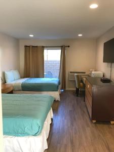 een hotelkamer met 3 bedden en een bureau bij Delos Reyes Palm Springs in Palm Springs