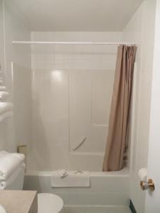 een witte badkamer met een bad en een toilet bij Lazy J Motel in Claresholm