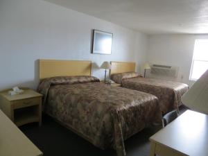 Lazy J Motel في Claresholm: غرفة فندقية بسريرين وطاولة