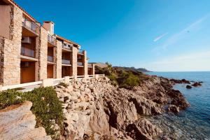 a building on a cliff next to the ocean at Hôtel du Golfe in Sartène