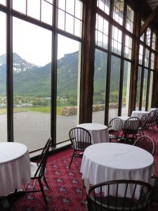 a room with tables and chairs and a view of the water at Prince of Wales Hotel in Waterton Park