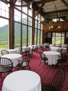 een kamer met witte tafels, stoelen en ramen bij Prince of Wales Hotel in Waterton Park