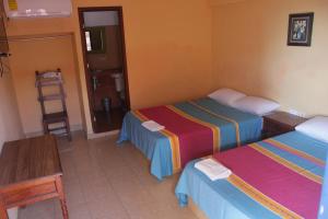 a room with two beds and a table and a chair at Hotel Progreso in Progreso