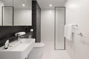 a white bathroom with a sink and a toilet at Modern, new 2 bed in the heart of Darling Harbour in Sydney