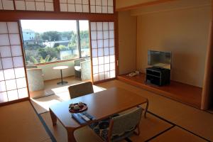 a living room with a table and a television at Kashikojima Hotel Bay Garden in Shima
