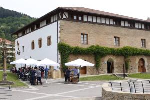 eine Gruppe von Personen, die vor einem Gebäude mit Sonnenschirmen stehen in der Unterkunft Hotel Dolarea in Beasain