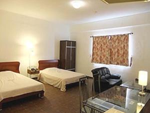 a hotel room with two beds and a chair at Himawari Hotel in Garapan