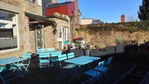 un groupe de tables et de chaises bleues à l'extérieur d'un bâtiment dans l'établissement Hôtel Patton, à Avranches