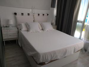 łóżko z białymi prześcieradłami i poduszkami w sypialni w obiekcie Moderno apartamento Torremolinos centro w mieście Torremolinos