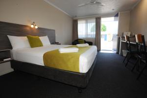 ein Hotelzimmer mit einem großen Bett und einem Schreibtisch in der Unterkunft Shoredrive Motel in Townsville