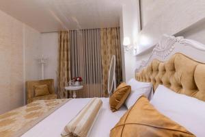 um quarto com uma grande cama branca e uma cadeira em Iberia Palace Hotel em Zugdidi