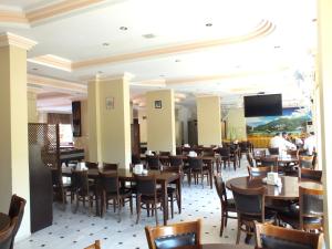 a dining room with tables and chairs and a flat screen tv at Grand Didyma Hotel in Didim