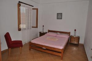 a bedroom with a bed and a red chair at MILTIADIS APARTMENTS in Andros