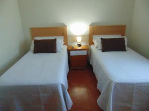 two beds in a bedroom with a lamp on a night stand at Aeropuerto in Carrizal
