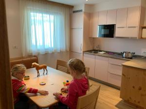 dos niños sentados en una mesa jugando con juguetes en Residence Bannwald, en Valle di Casies