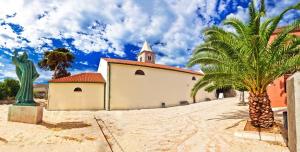 una iglesia con una palmera al lado de un edificio en Apartment Selman, en Nin