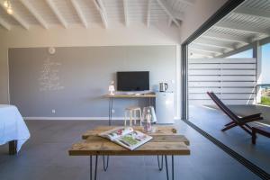 uma sala de estar com uma mesa e uma televisão em Villa Jwi Lavi Boutique Hotel em São Martinho