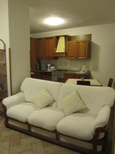uma sala de estar com um sofá branco e uma cozinha em Casa Soldino em Laglio