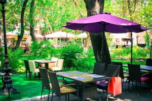 un ombrellone viola seduto accanto a tavoli e sedie di Hotel MAMAN a Odessa