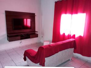 a living room with a tv and red curtains at Pousada da Ana in Cavalcante