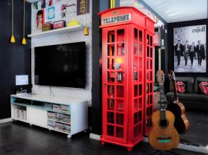 - une cabine de téléphone rouge dans une pièce avec une guitare dans l'établissement Vila Rock Hostel - próximo Allianz Parque, Vila Madalena, Av Paulista, Hospital das Clínicas INCOR FMUSP, à São Paulo