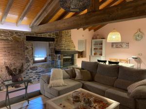 a living room with a couch and a stone fireplace at C'Genoveva Complejo Turistico Rural CaleaCabo in Biescas