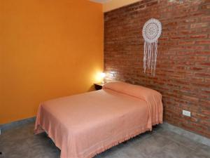 1 dormitorio con cama y pared de ladrillo en Las Grutas 5M en Las Grutas