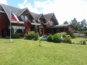 una casa roja con una bandera en el patio en Hostal Möller en Villarrica