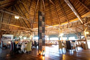 a dining room with tables and chairs in a building at Crater Safari Lodge in Kibale Forest National Park