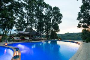 a large blue swimming pool with chairs and trees at Crater Safari Lodge in Kibale Forest National Park