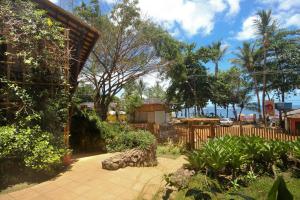 a garden with a wooden fence and trees and the ocean at Concha Tropical Flat in Itacaré