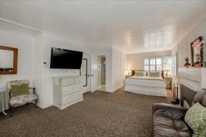 a large white bedroom with a bed and a tv at Carmel Green Lantern Inn in Carmel